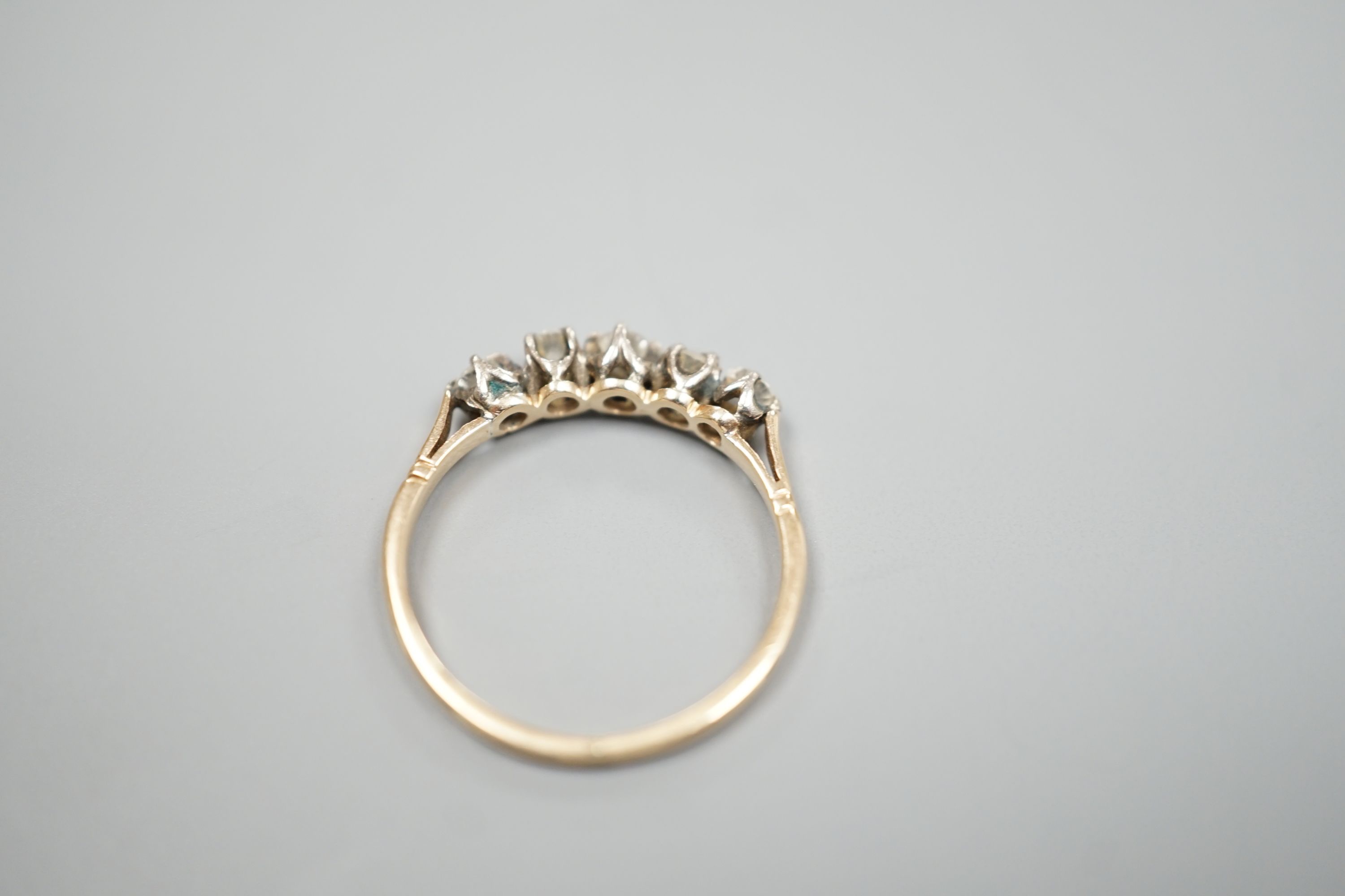 A yellow metal and five stone diamond set half hoop ring, size M, gross weight 1.6 grams.